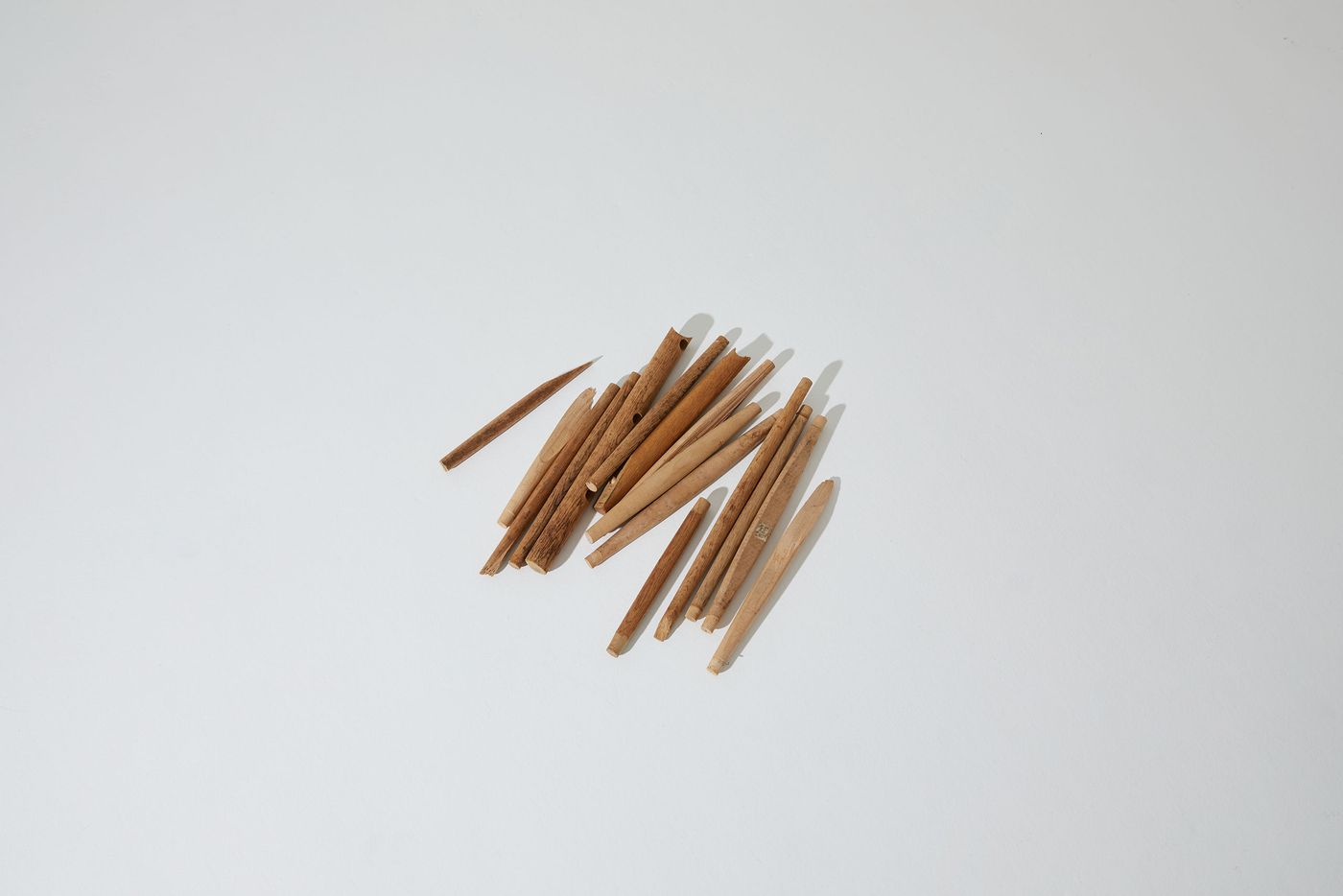 A scattered collection of wooden sticks of varying lengths, arranged loosely on a plain white surface. A scattered collection of wooden sticks of varying lengths, arranged loosely on a plain white surface.