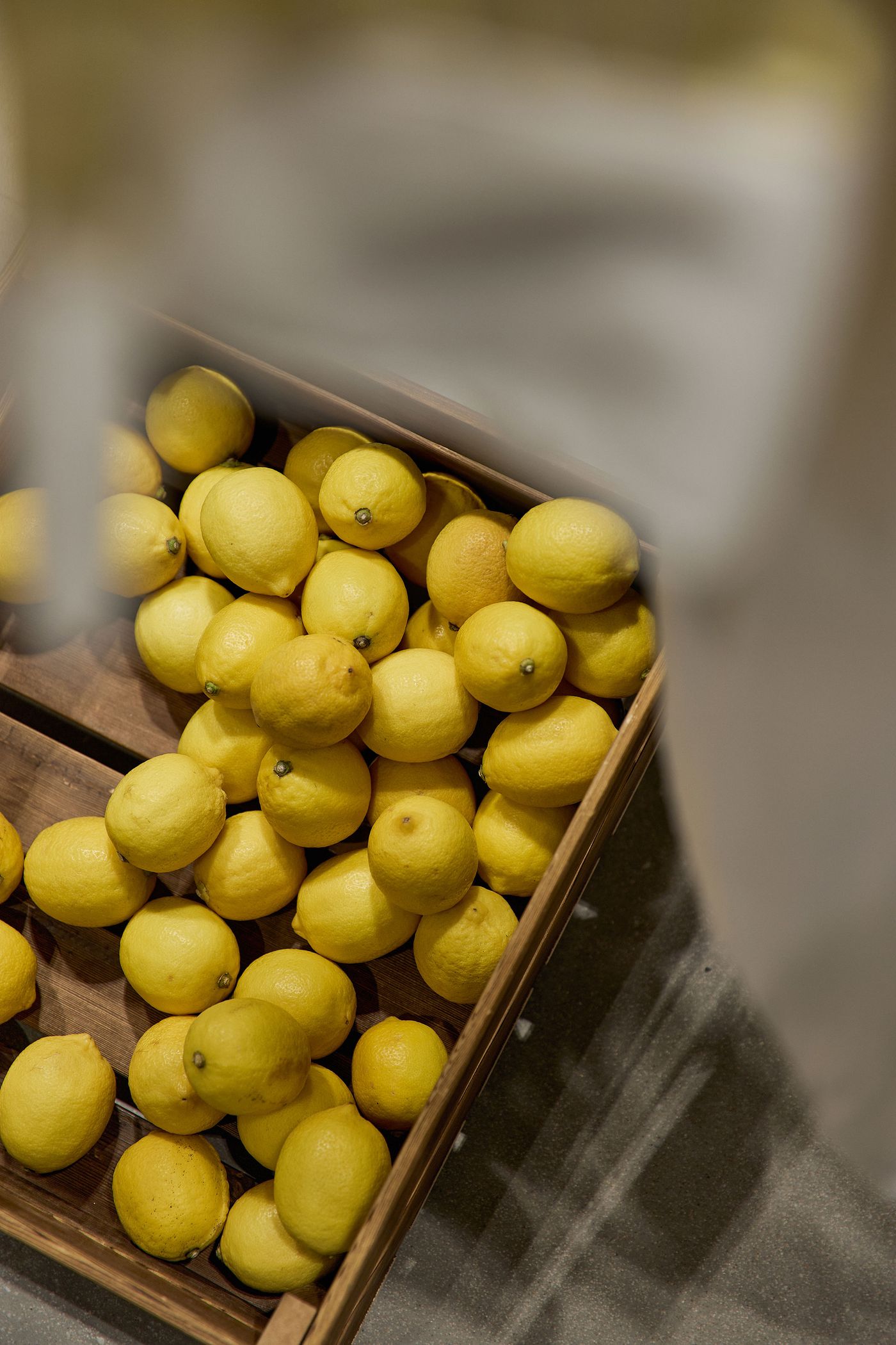 A wooden crate filled with vibrant yellow lemons, arranged closely together on a textured surface. A wooden crate filled with vibrant yellow lemons, arranged closely together on a textured surface.
