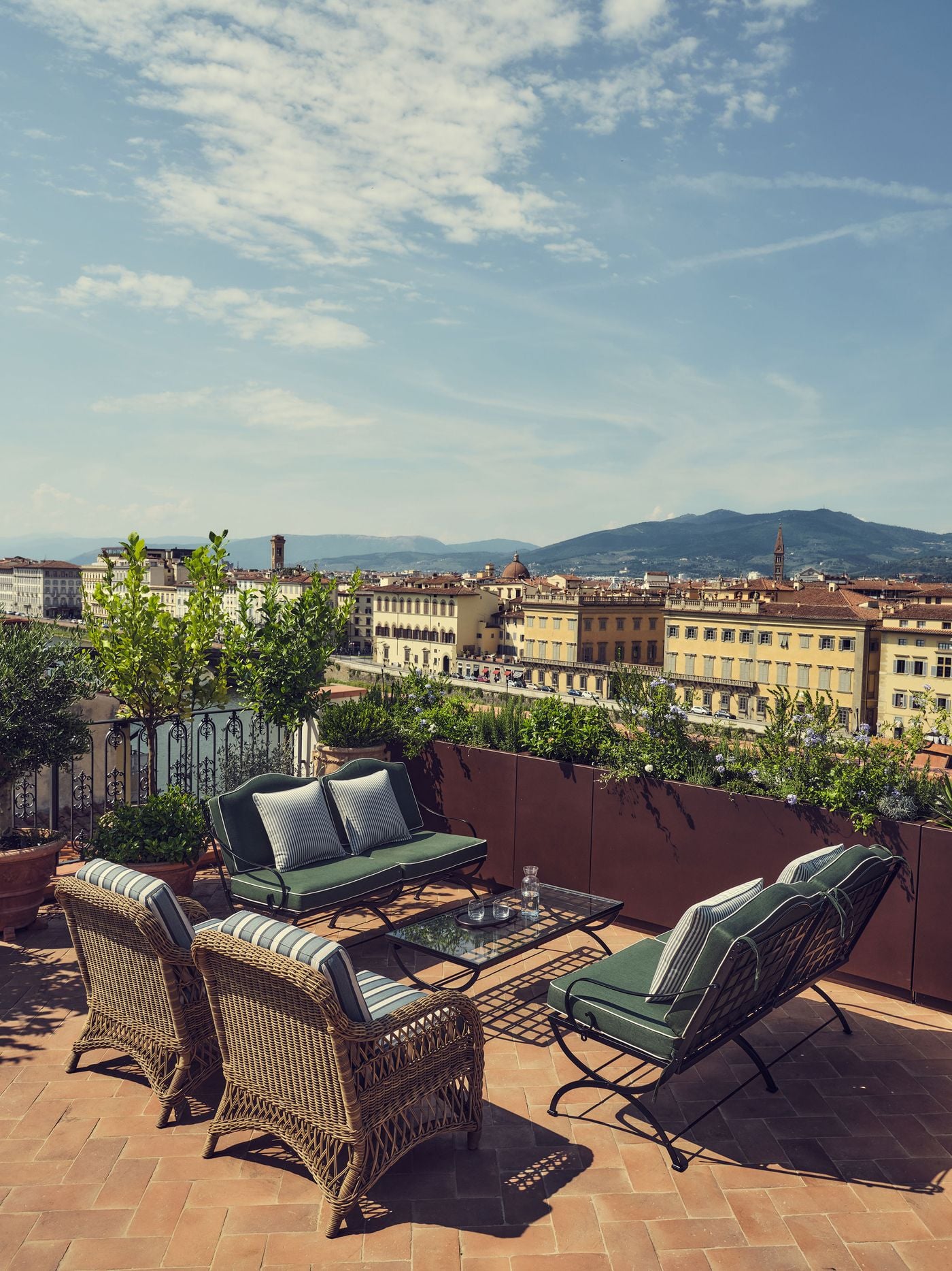 Under a wide summer sky, the rooftop terrace of La Réserve Firenze gathers wrought-iron and wicker seating on a herringbone terracotta floor. Beyond the planted parapet and an iron balustrade, the Arno and its lungarno palazzi lead the eye towards the Tuscan hills. Under a wide summer sky, the rooftop terrace of La Réserve Firenze gathers wrought-iron and wicker seating on a herringbone terracotta floor. Beyond the planted parapet and an iron balustrade, the Arno and its lungarno palazzi lead the eye towards the Tuscan hills.