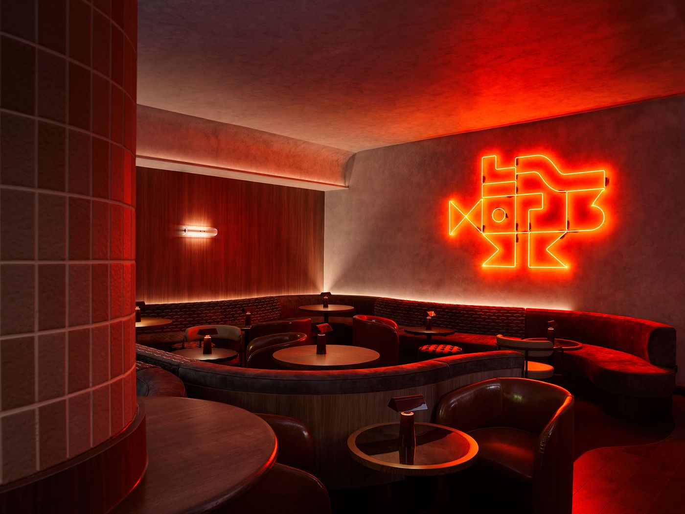 A dimly lit lounge features cozy seating, wooden tables, and an eye-catching neon sign against a textured wall. A dimly lit lounge features cozy seating, wooden tables, and an eye-catching neon sign against a textured wall.