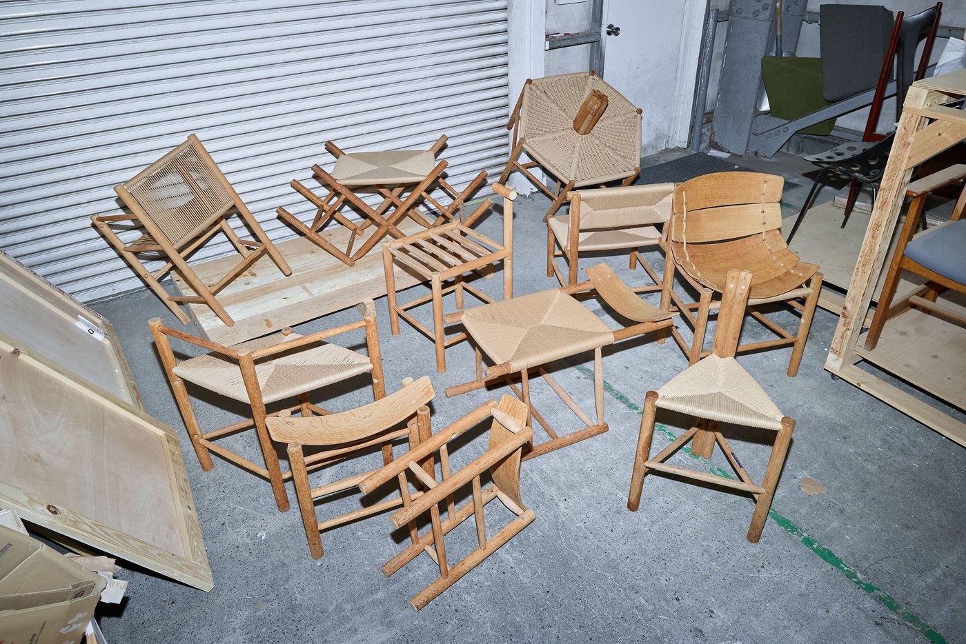 A collection of various wooden chairs with woven seats in a cluttered space, showcasing different designs and styles. A collection of various wooden chairs with woven seats in a cluttered space, showcasing different designs and styles.