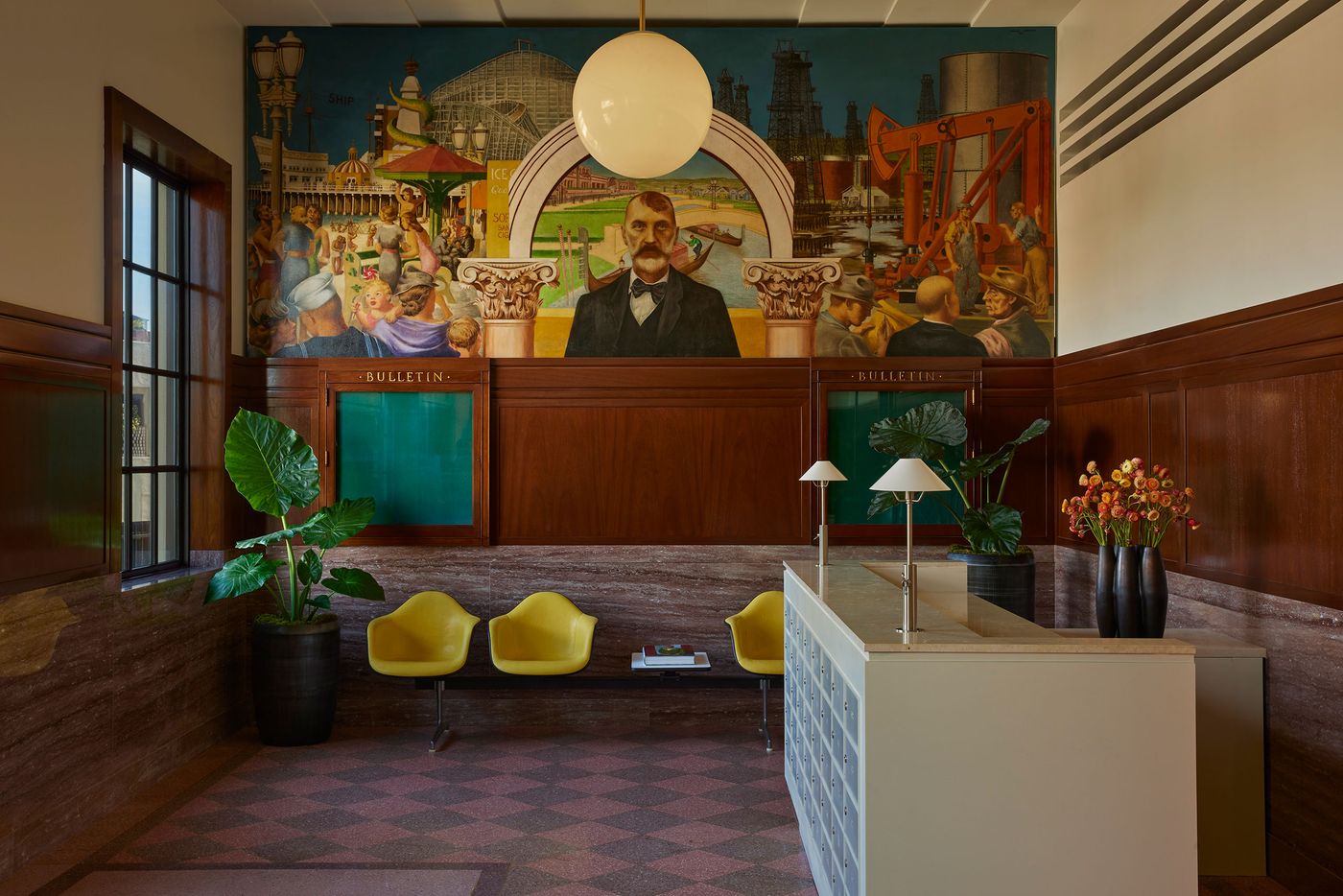 A stylish reception area featuring modern yellow chairs, a wooden counter, and a vibrant mural depicting historical scenes. A stylish reception area featuring modern yellow chairs, a wooden counter, and a vibrant mural depicting historical scenes.