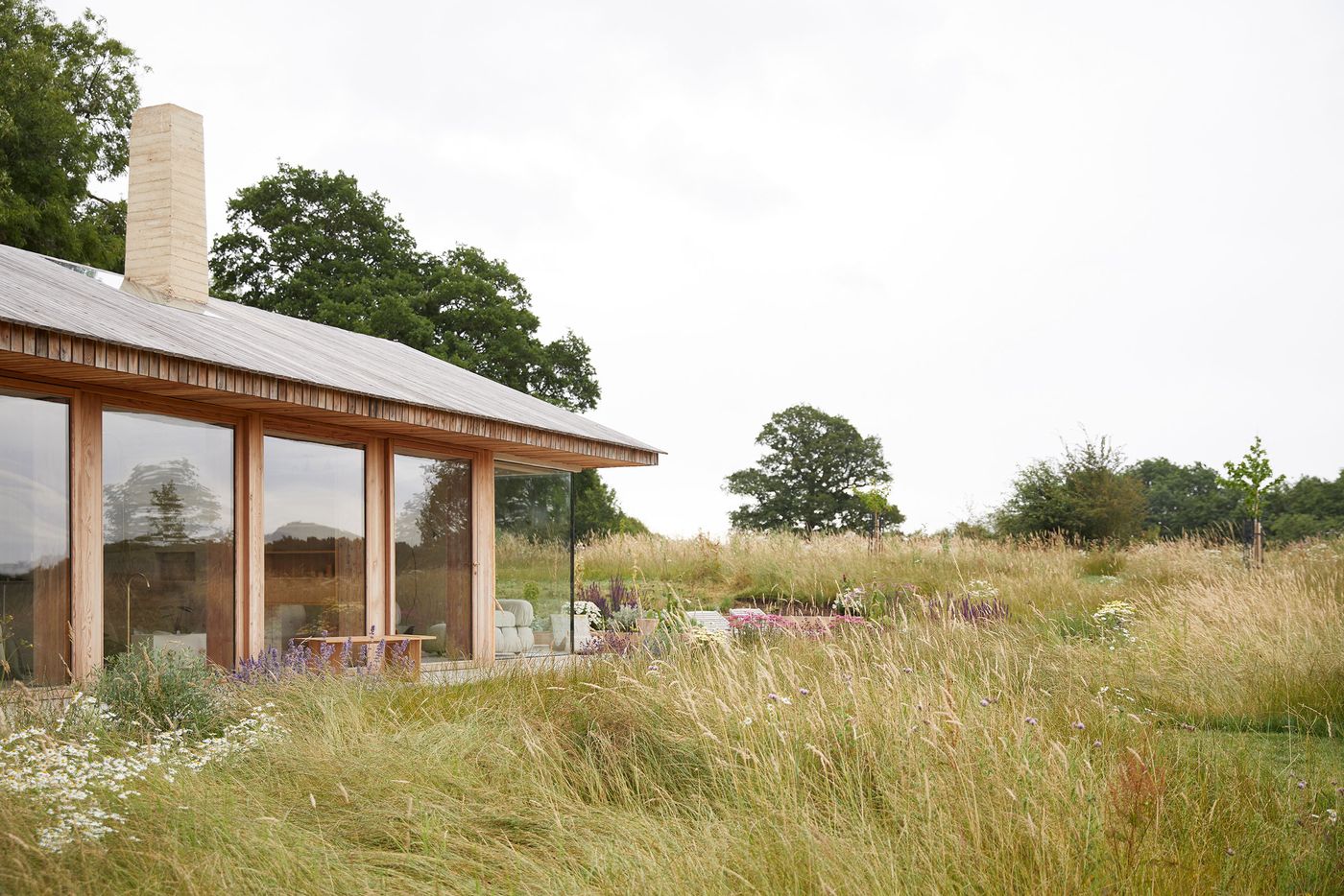 The Maker's Barn by Hutch Design exemplifies biophilic and minimalist design, nestled within a wild meadow. Its long, low profile with extensive timber-framed windows reflects the surrounding natural landscape. The subtle chimney and simple lines create a harmonious balance between refined architecture and the untamed beauty of the British countryside. The Maker's Barn by Hutch Design exemplifies biophilic and minimalist design, nestled within a wild meadow. Its long, low profile with extensive timber-framed windows reflects the surrounding natural landscape. The subtle chimney and simple lines create a harmonious balance between refined architecture and the untamed beauty of the British countryside.
