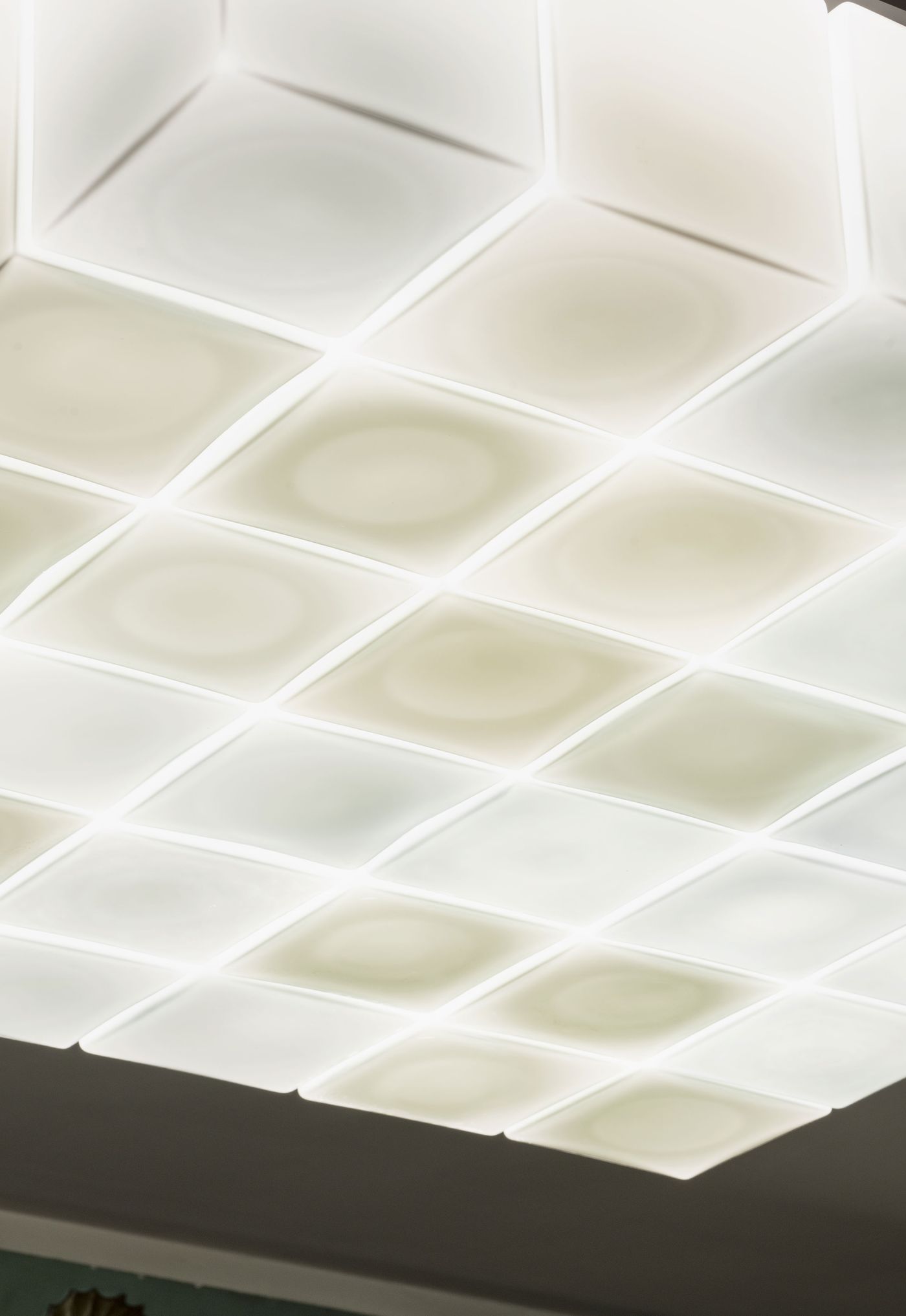 Close-up of a sculptural ceiling light made of luminous, soft-edged glass squares.