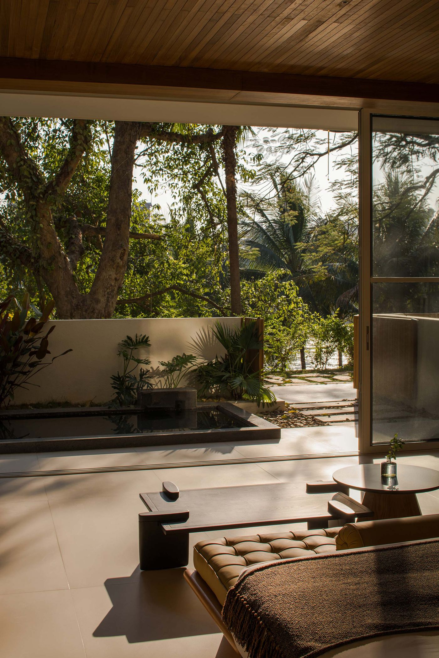 A serene interior view showcasing a cozy living space, surrounded by lush greenery and natural light filtering through large windows.
