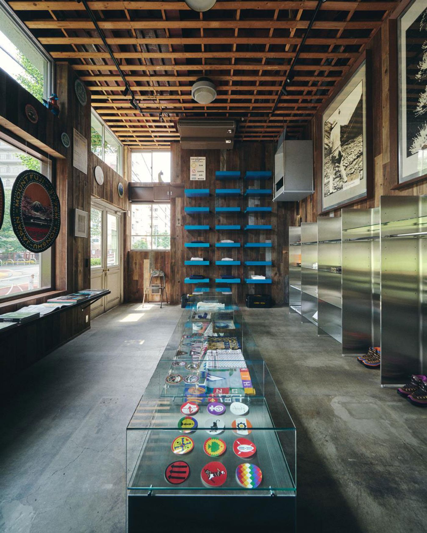 Interior of a trendy retail space featuring wooden walls, blue shelves, a glass display of colorful patches, and sleek stainless steel fixtures.