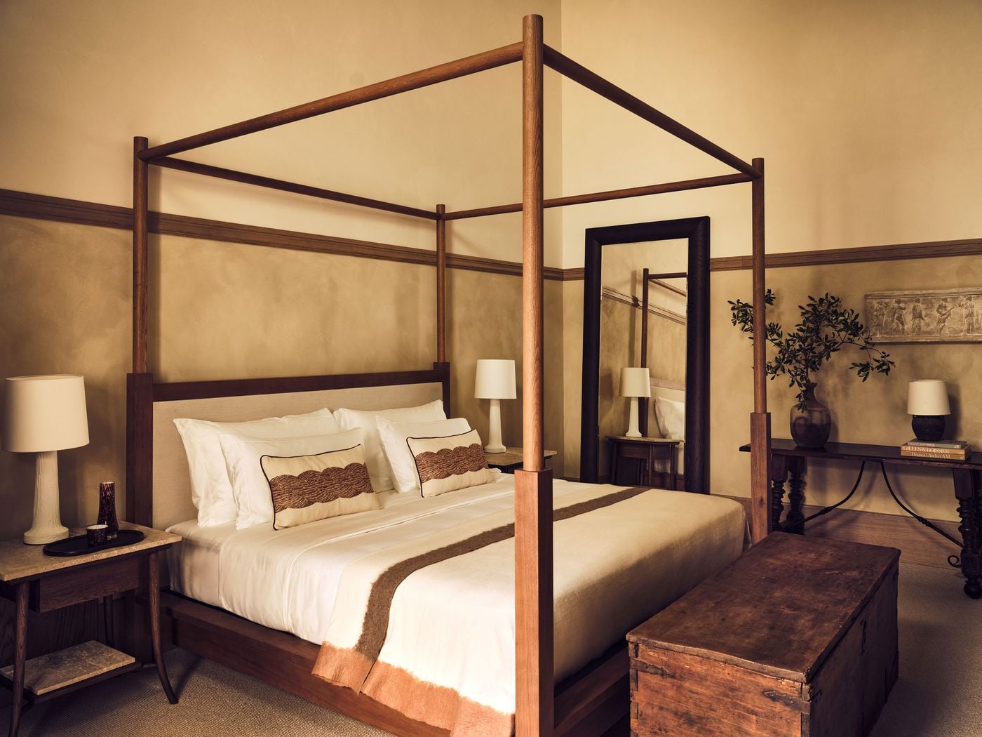 A pared-back oak four-poster bed occupies a bedroom at La Réserve Firenze, its walls divided into two warm ochre tones by a timber dado rail. An antique chest, a leaning dark-framed mirror and a classical relief above a turned-leg console add texture and history to the calm, enveloping scheme. A pared-back oak four-poster bed occupies a bedroom at La Réserve Firenze, its walls divided into two warm ochre tones by a timber dado rail. An antique chest, a leaning dark-framed mirror and a classical relief above a turned-leg console add texture and history to the calm, enveloping scheme.