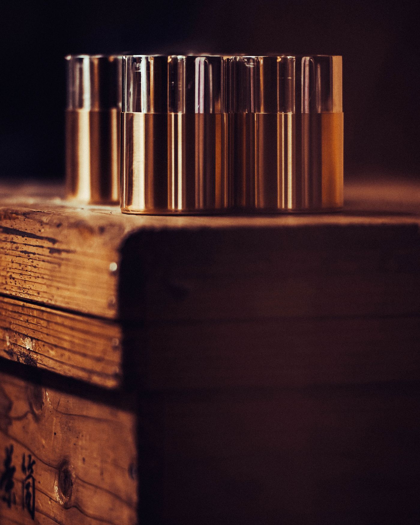 Four elegant metallic capsules on a rustic wooden surface, illuminated softly.