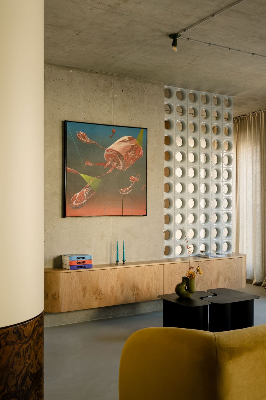 Viewed from behind a mustard sofa, the scene highlights the dynamic interplay between a surrealist artwork, sculptural furniture, and rounded architectural elements. Mistovia’s signature blend of industrial rawness and curated softness is on full display. Viewed from behind a mustard sofa, the scene highlights the dynamic interplay between a surrealist artwork, sculptural furniture, and rounded architectural elements. Mistovia’s signature blend of industrial rawness and curated softness is on full display.