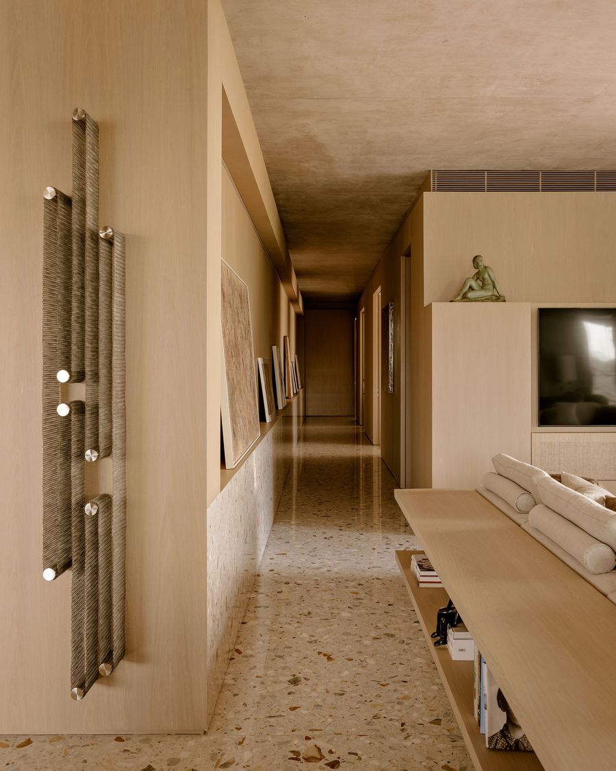 A sleek, modern hallway features wooden walls, a stone floor, art pieces, and a minimalistic bench, creating a serene atmosphere. A sleek, modern hallway features wooden walls, a stone floor, art pieces, and a minimalistic bench, creating a serene atmosphere.