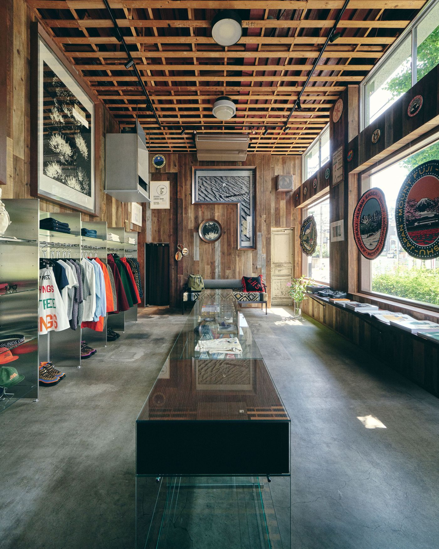 Interior of a stylish boutique featuring wooden walls, colorful apparel displays, and large windows letting in natural light.