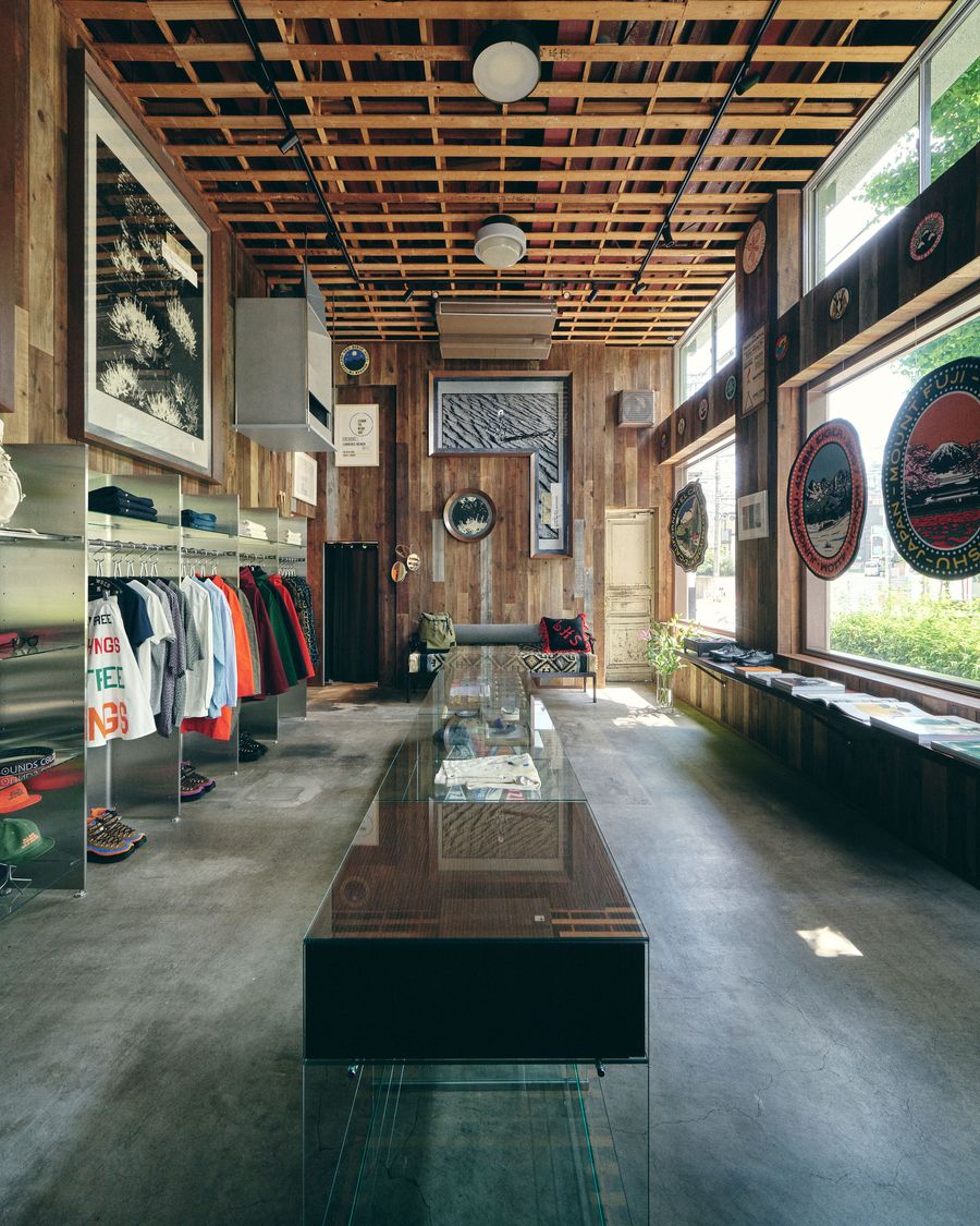 Interior of a stylish boutique featuring wooden walls, colorful apparel displays, and large windows letting in natural light.