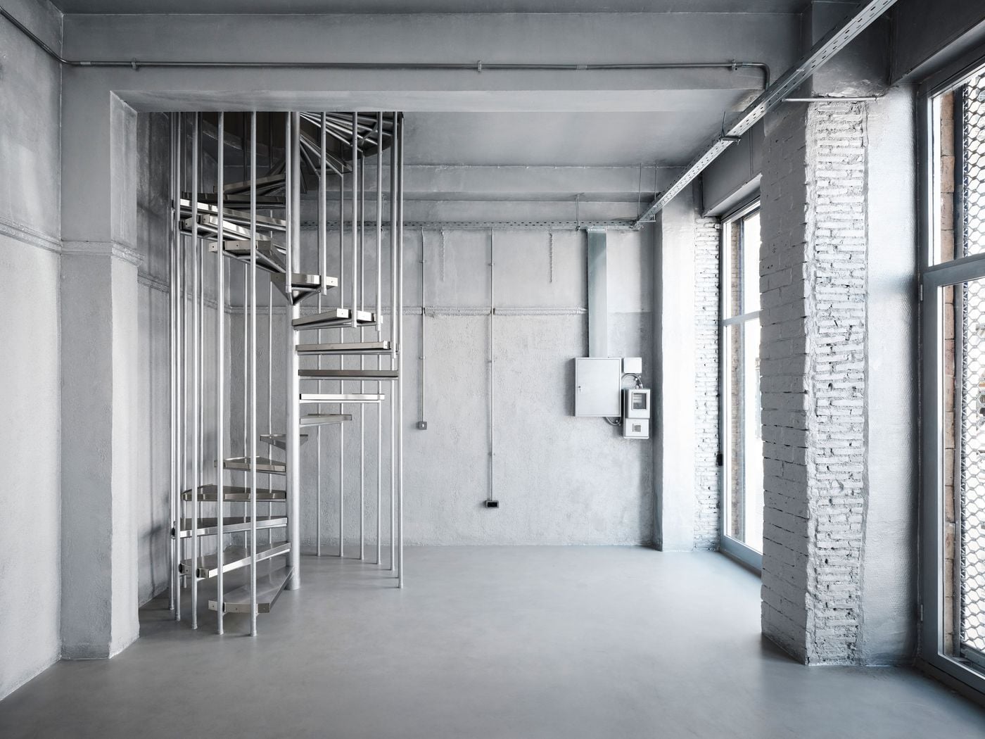 The corner gallery space takes on an almost monochromatic character, with walls, ceiling, exposed services and a new spiral staircase enveloped in a silvery liquid-metal finish. Daylight from tall street-facing windows accentuates subtle variations in texture, transforming the warehouse’s most extensively altered section into a distinctly contemporary counterpoint to its raw masonry spaces. The corner gallery space takes on an almost monochromatic character, with walls, ceiling, exposed services and a new spiral staircase enveloped in a silvery liquid-metal finish. Daylight from tall street-facing windows accentuates subtle variations in texture, transforming the warehouse’s most extensively altered section into a distinctly contemporary counterpoint to its raw masonry spaces.