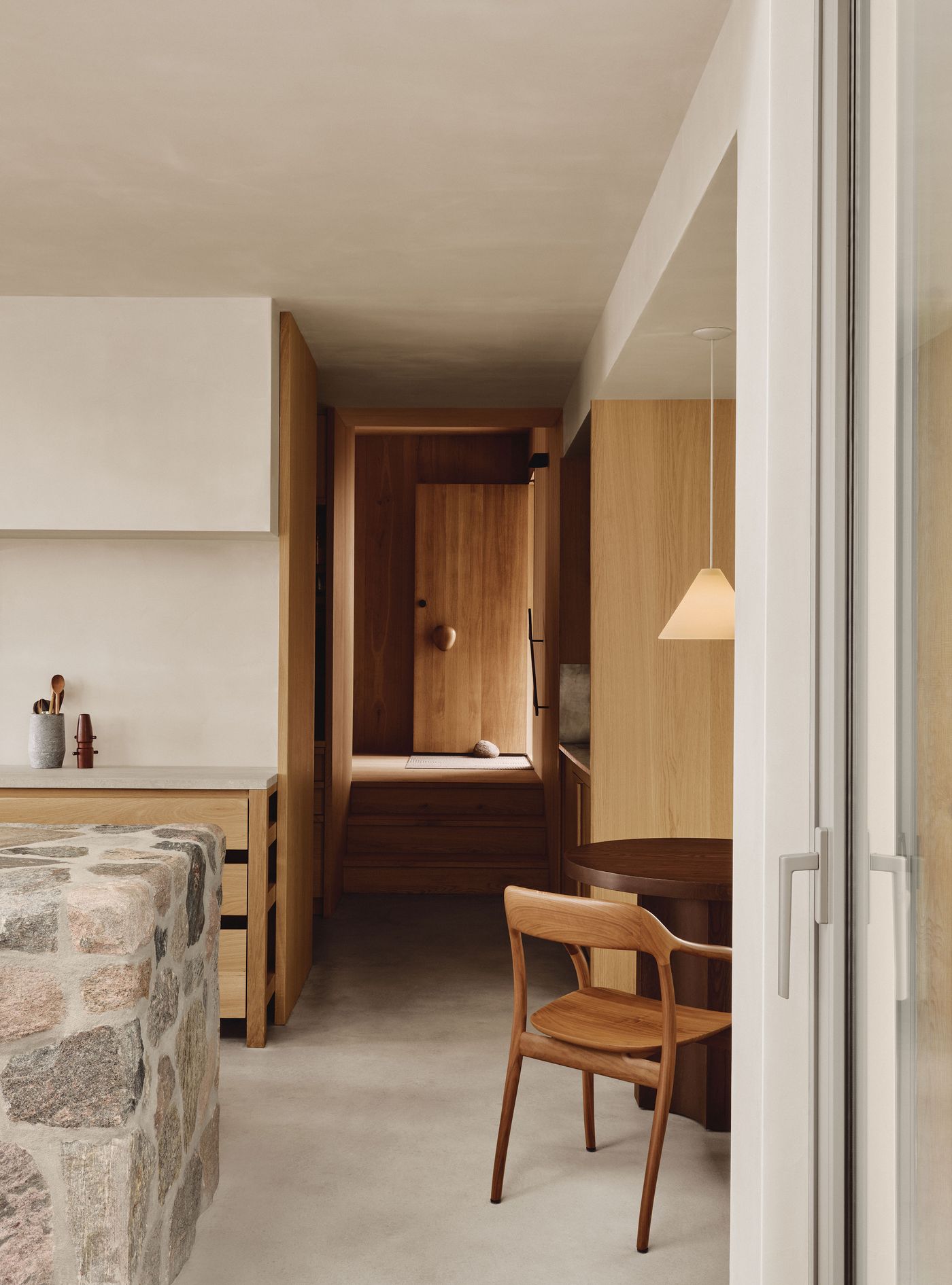A modern, minimalist interior featuring wood accents, a stone countertop, a round table with a chair, and a warm, inviting atmosphere. A modern, minimalist interior featuring wood accents, a stone countertop, a round table with a chair, and a warm, inviting atmosphere.