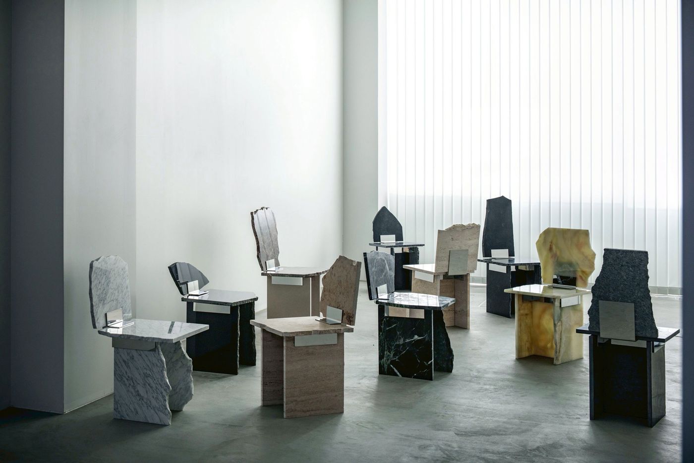 A collection of uniquely designed chairs made from various types of stone, arranged in a minimalistic, modern interior setting. A collection of uniquely designed chairs made from various types of stone, arranged in a minimalistic, modern interior setting.