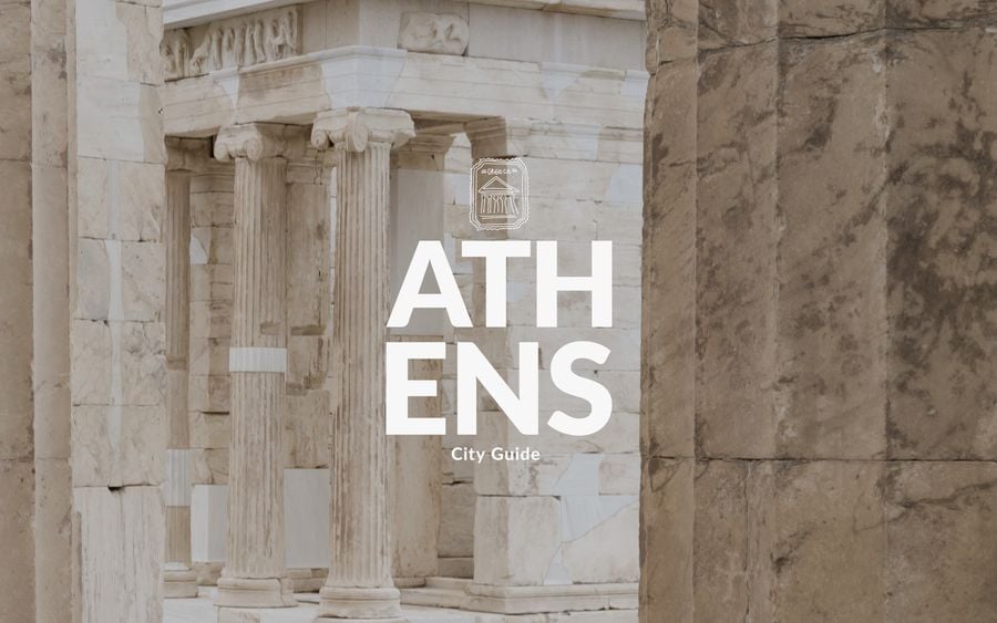 Athens City Guide by Yatzer, cover with bold white lettering and a hand-drawn Greece stamp of the Parthenon, set over a close-up of the Acropolis Propylaea’s weathered marble Ionic columns, sculpted frieze, and sunlit stone walls in warm neutral tones. Athens City Guide by Yatzer, cover with bold white lettering and a hand-drawn Greece stamp of the Parthenon, set over a close-up of the Acropolis Propylaea’s weathered marble Ionic columns, sculpted frieze, and sunlit stone walls in warm neutral tones.