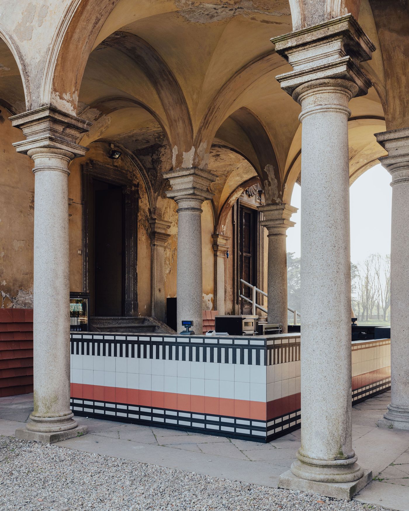 A tiled bar installation pops with graphic patterns beneath arched stone colonnades—old-world architecture meets Memphis spirit.