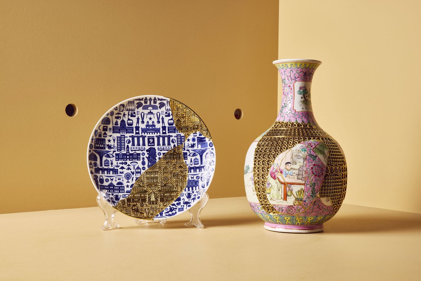 A blue-and-white ceramic plate and a colorful vase, each intricately repaired with delicate golden latticework, displayed against a mustard yellow background.