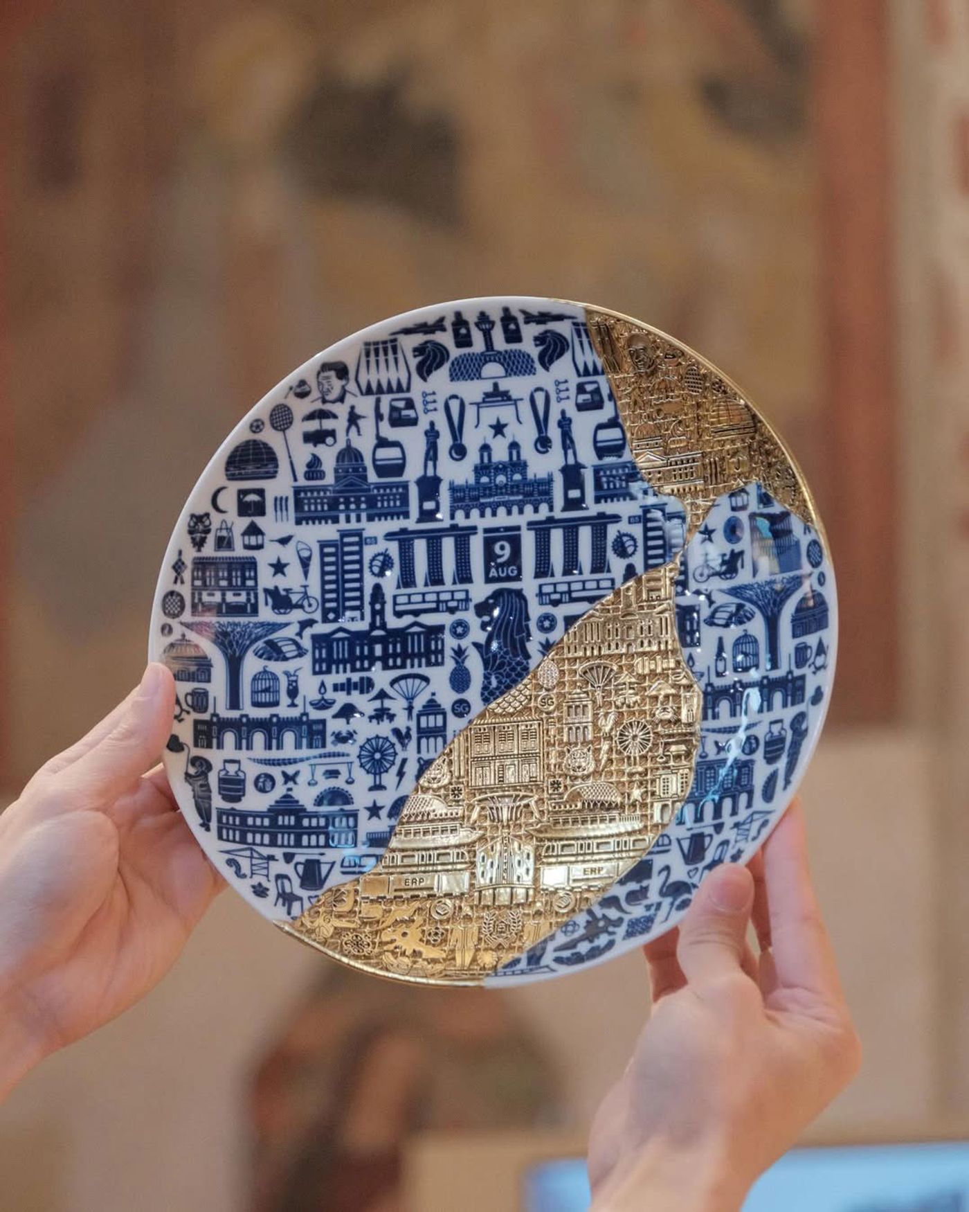 Hands holding up a restored blue-and-white plate with golden lattice seamlessly filling in missing parts.