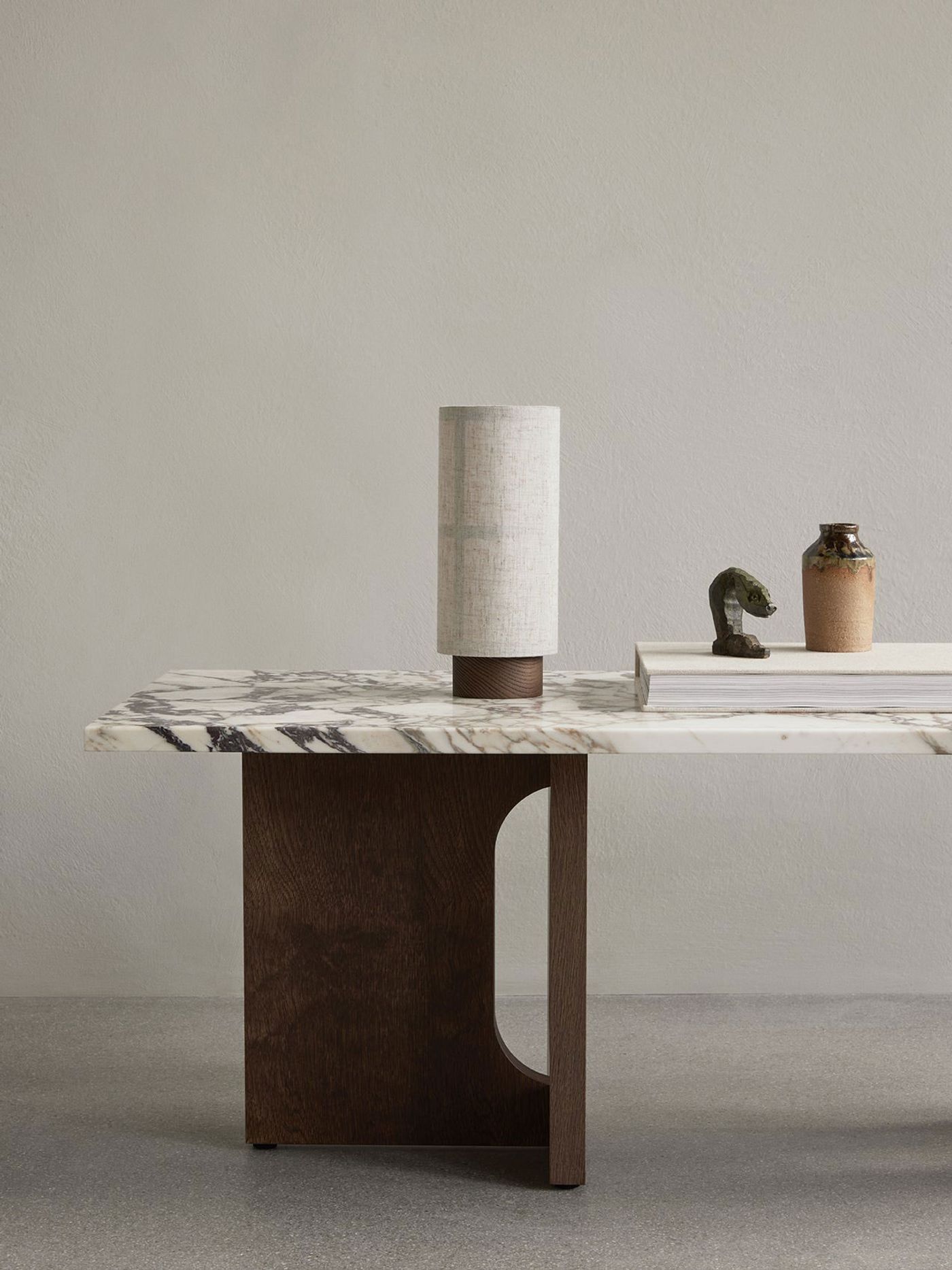 The portable Hashira Table Lamp by Norm Architects for Audo sits on a sculptural marble-and-wood Androgyne Lounge Table, casting a soft, architectural glow. The portable Hashira Table Lamp by Norm Architects for Audo sits on a sculptural marble-and-wood Androgyne Lounge Table, casting a soft, architectural glow.