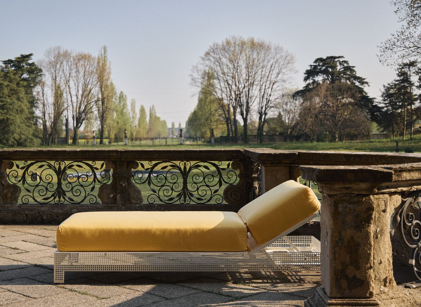 Lemon’s sleek yellow-cushioned lounger placed on a stone terrace, with ornate iron balustrades and a sweeping view of the landscaped grounds. Lemon’s sleek yellow-cushioned lounger placed on a stone terrace, with ornate iron balustrades and a sweeping view of the landscaped grounds.