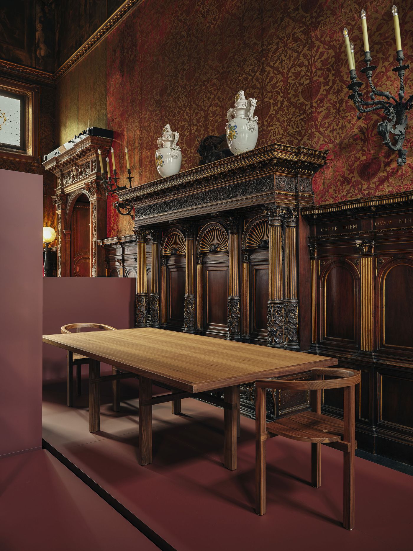 Minimalist wooden dining table with matching chairs, staged against richly decorated classical walls and intricate woodwork. Minimalist wooden dining table with matching chairs, staged against richly decorated classical walls and intricate woodwork.