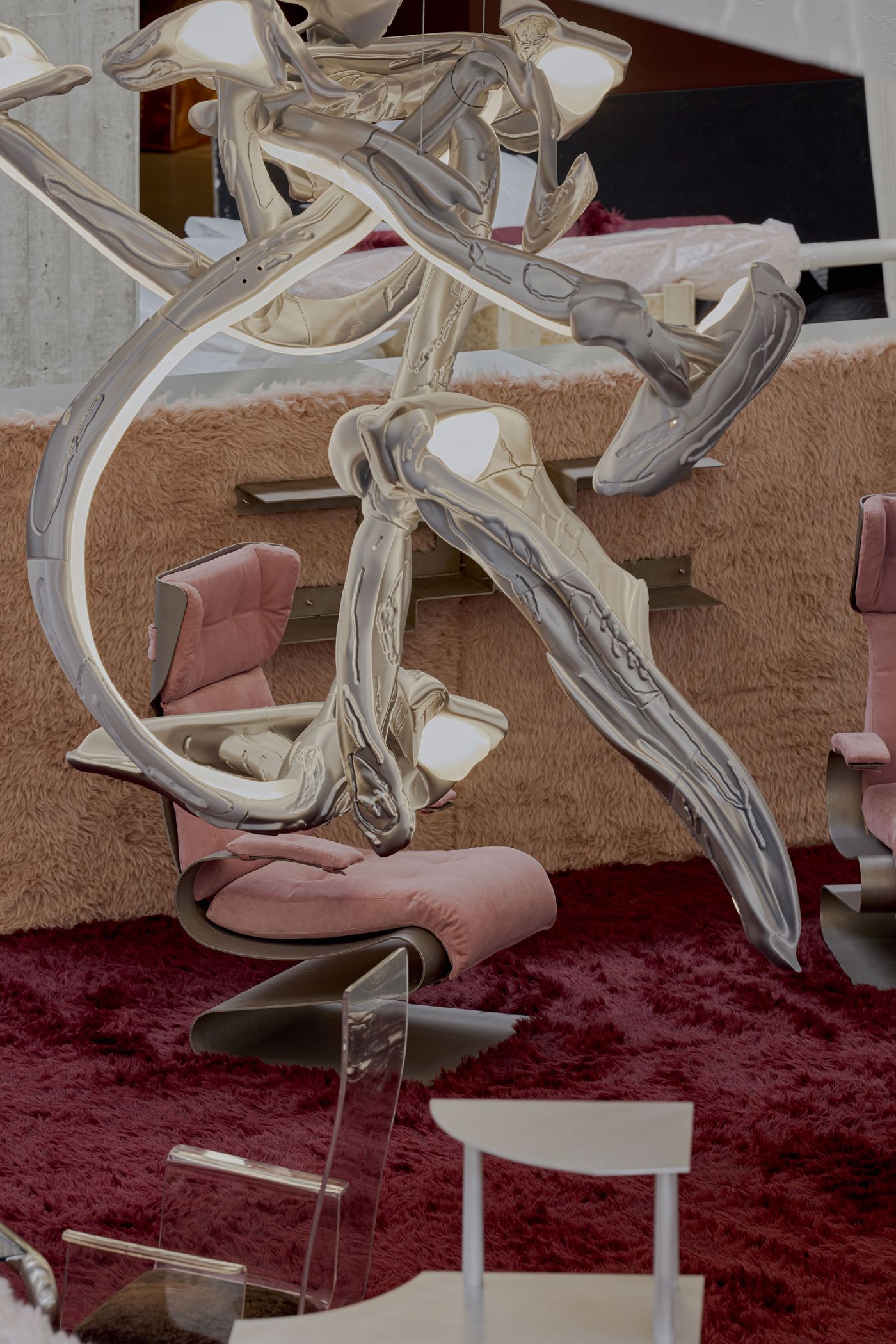 Sculptural lights twist like liquid metal through a dreamscape of pink shag and velvet—baroque cyber fantasy.