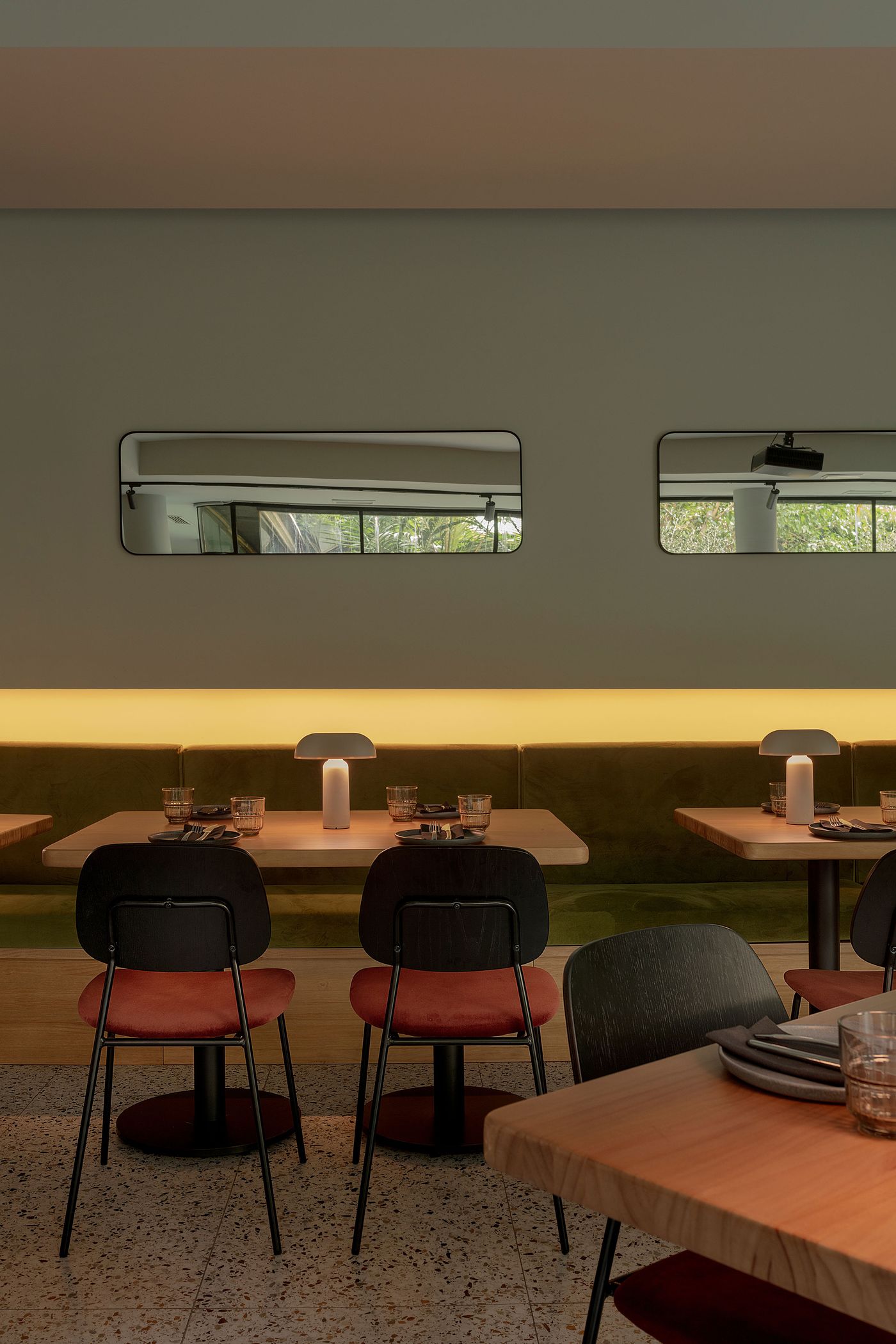 A trio of Porta table lamps cast a gentle light across restaurant tables, blending seamlessly with velvet banquettes and terrazzo floors.
