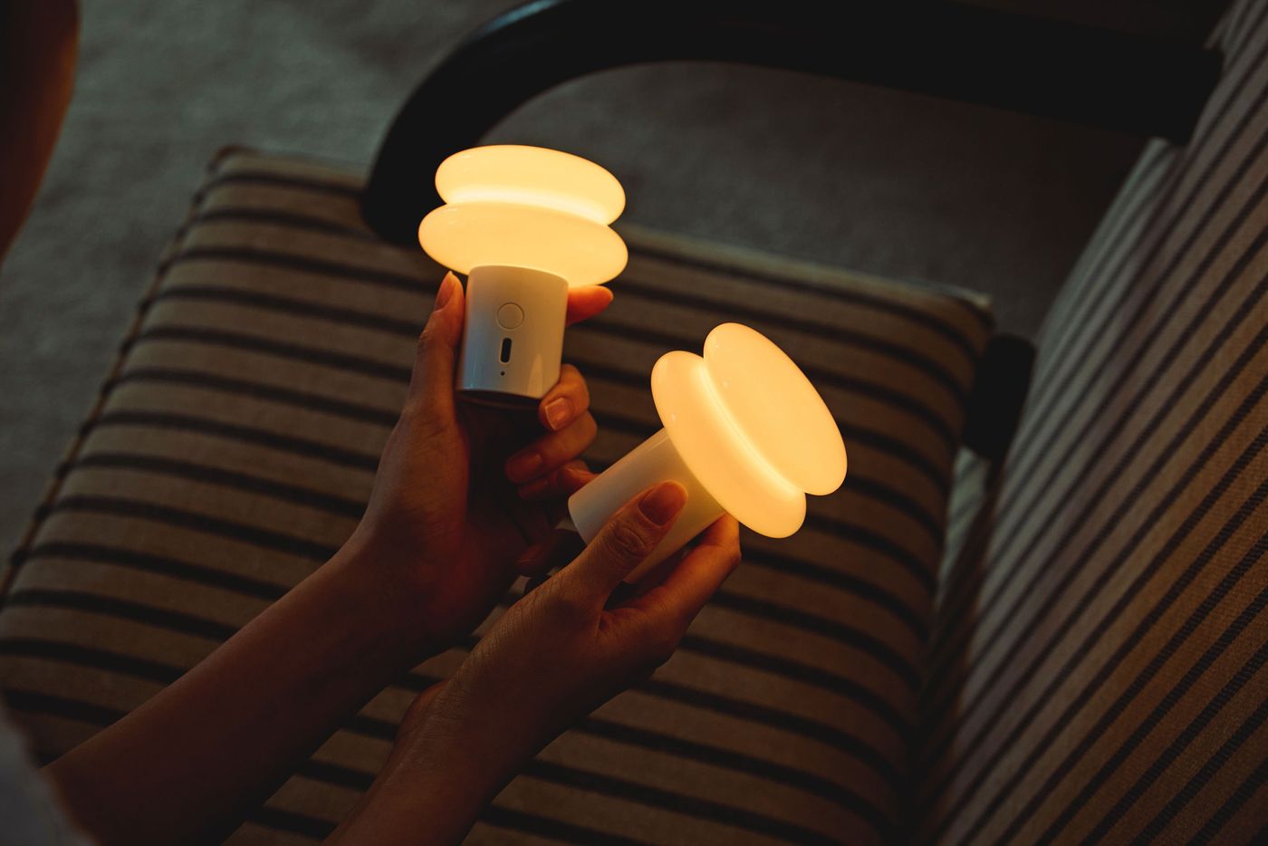 Two SNOWMAN lamps held in hand, showing their compact and sculptural design glowing warmly, ideal for intimate settings or portable use. Two SNOWMAN lamps held in hand, showing their compact and sculptural design glowing warmly, ideal for intimate settings or portable use.
