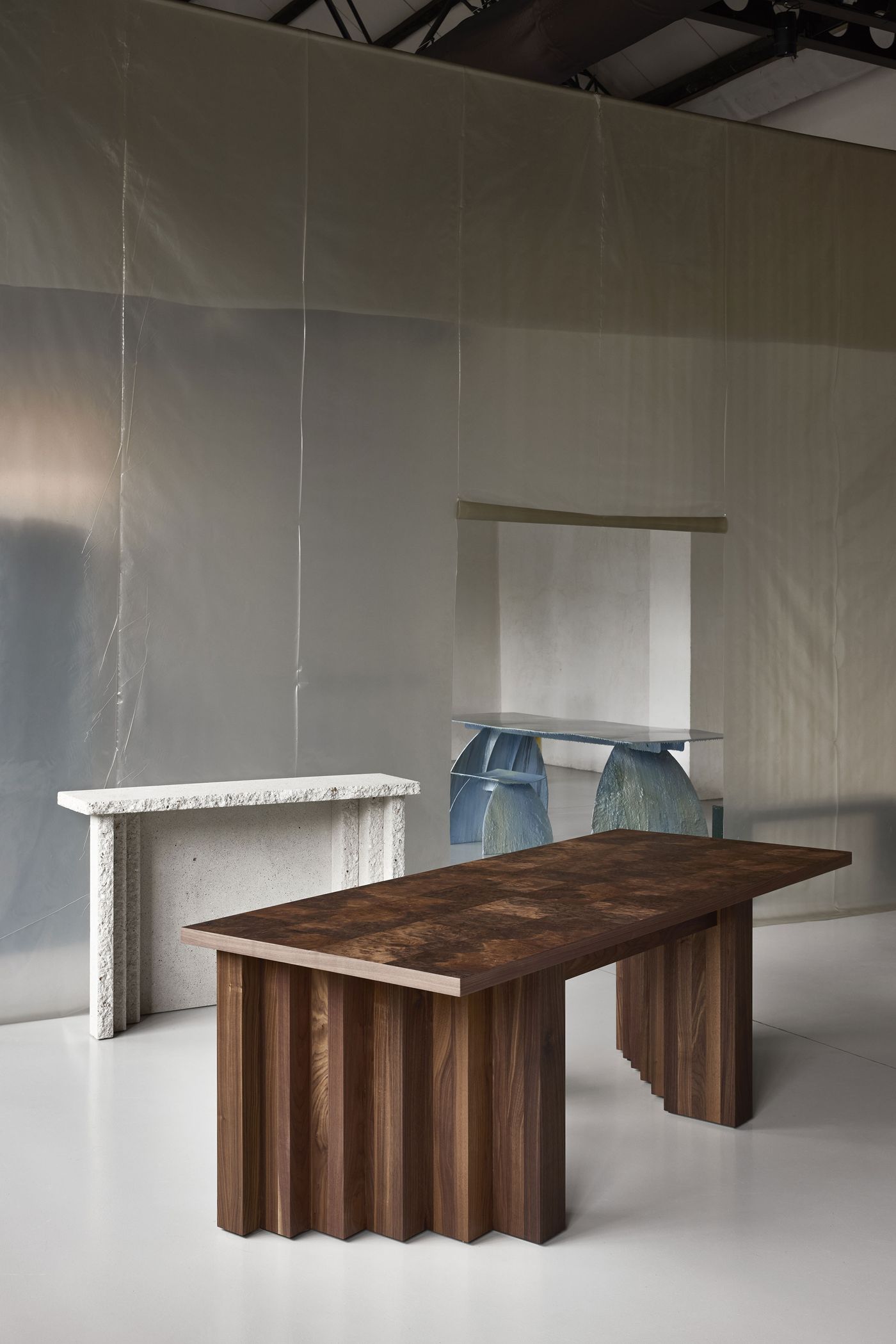 A solid wood dining table with fluted legs, set against a backdrop of textured, translucent panels. A solid wood dining table with fluted legs, set against a backdrop of textured, translucent panels.