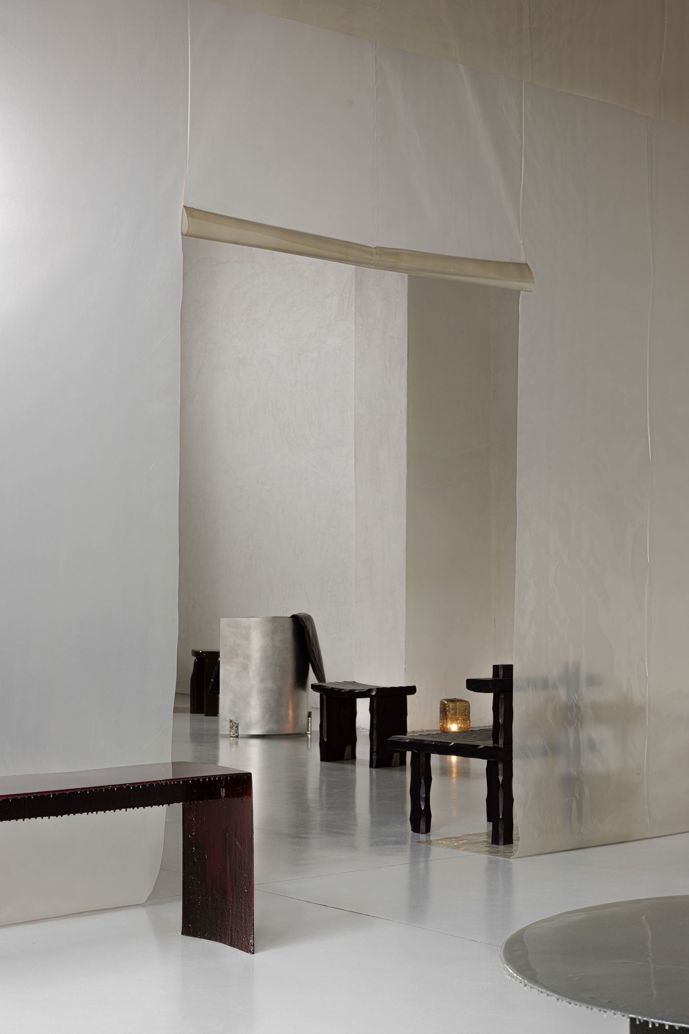 A serene, gallery-like interior with rustic dark wood stools and soft, ambient lighting creating a quiet mood. A serene, gallery-like interior with rustic dark wood stools and soft, ambient lighting creating a quiet mood.