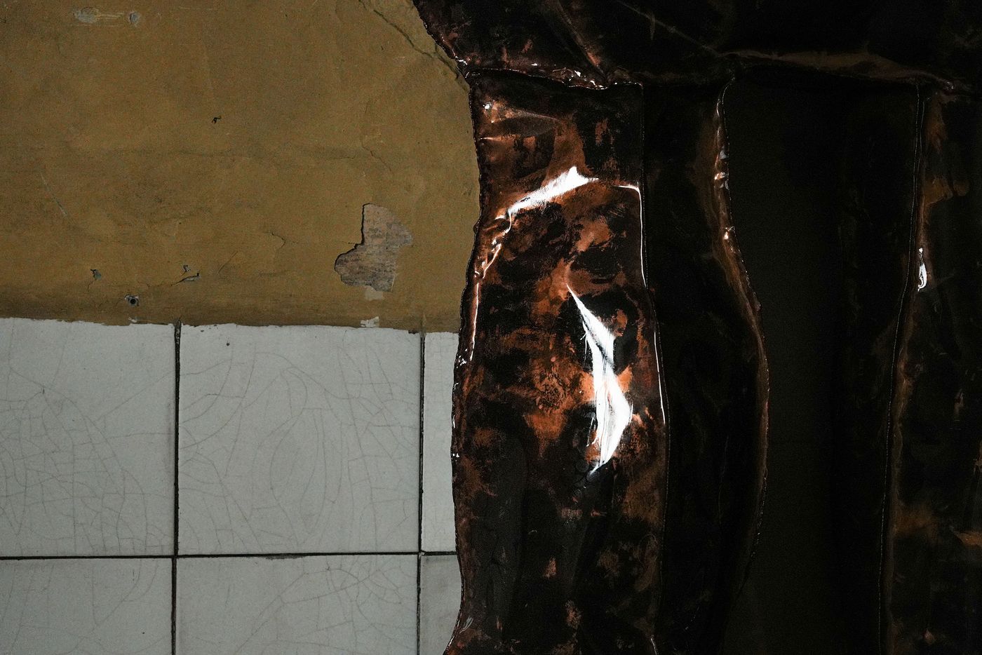 Close-up detail of the glossy sculptural surface, revealing its rich, marbled texture and reflections against cracked white tiles.