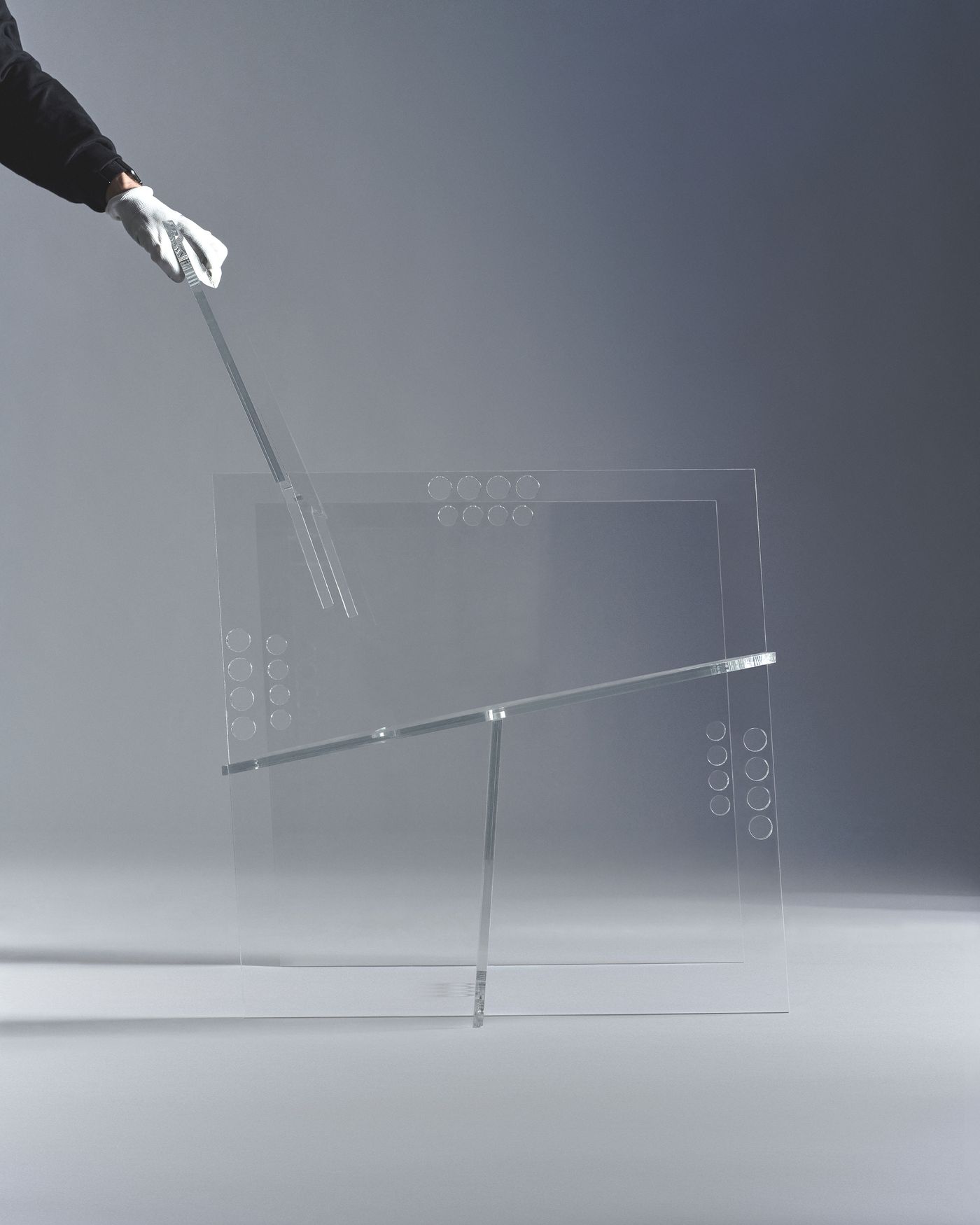 A hand wearing a white glove demonstrates the insertion of a sleek acrylic element into a matching transparent structure. A hand wearing a white glove demonstrates the insertion of a sleek acrylic element into a matching transparent structure.