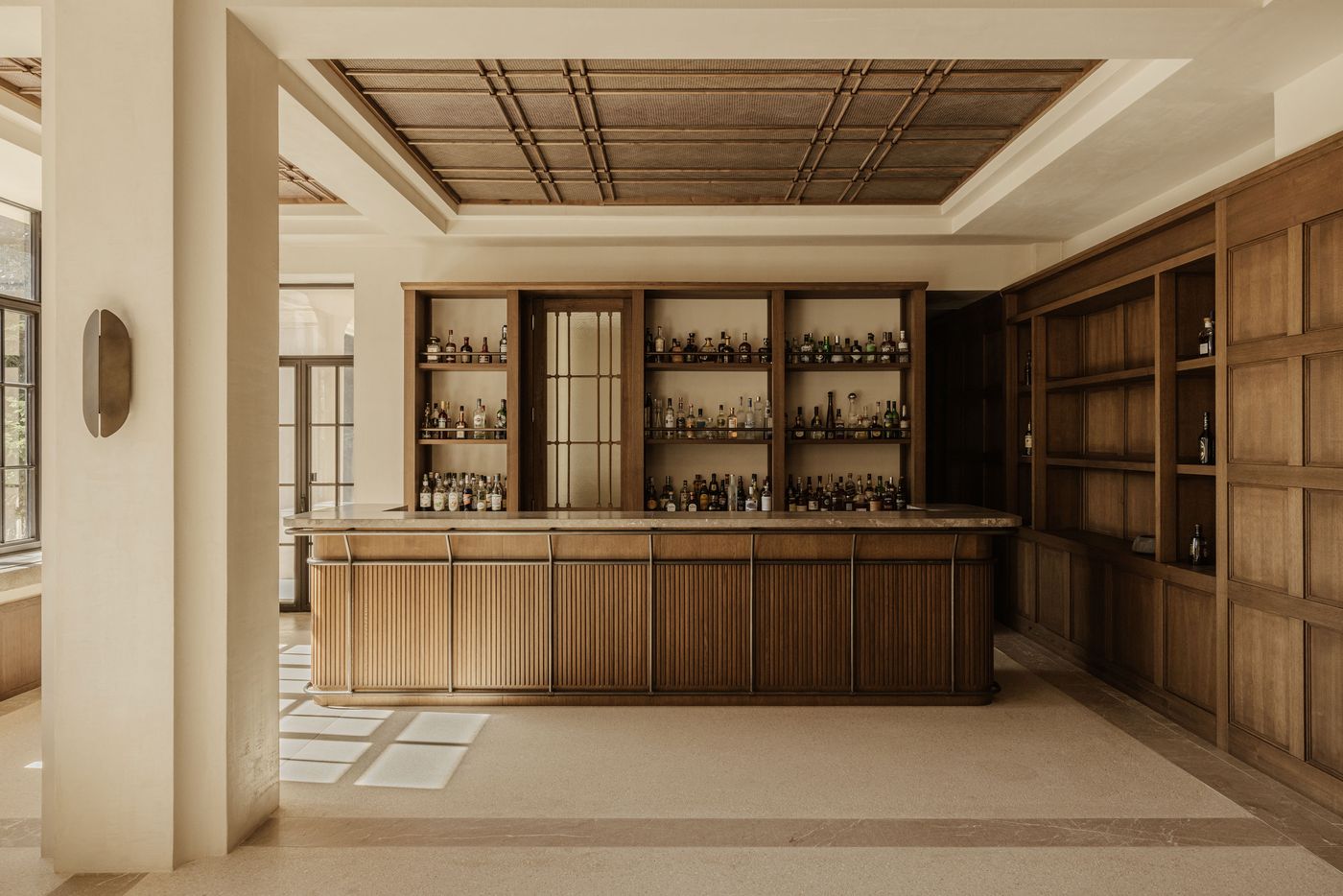 Sophisticated bar interior with fluted wooden cabinetry and backlit shelves showcasing an extensive spirits collection. Sophisticated bar interior with fluted wooden cabinetry and backlit shelves showcasing an extensive spirits collection.