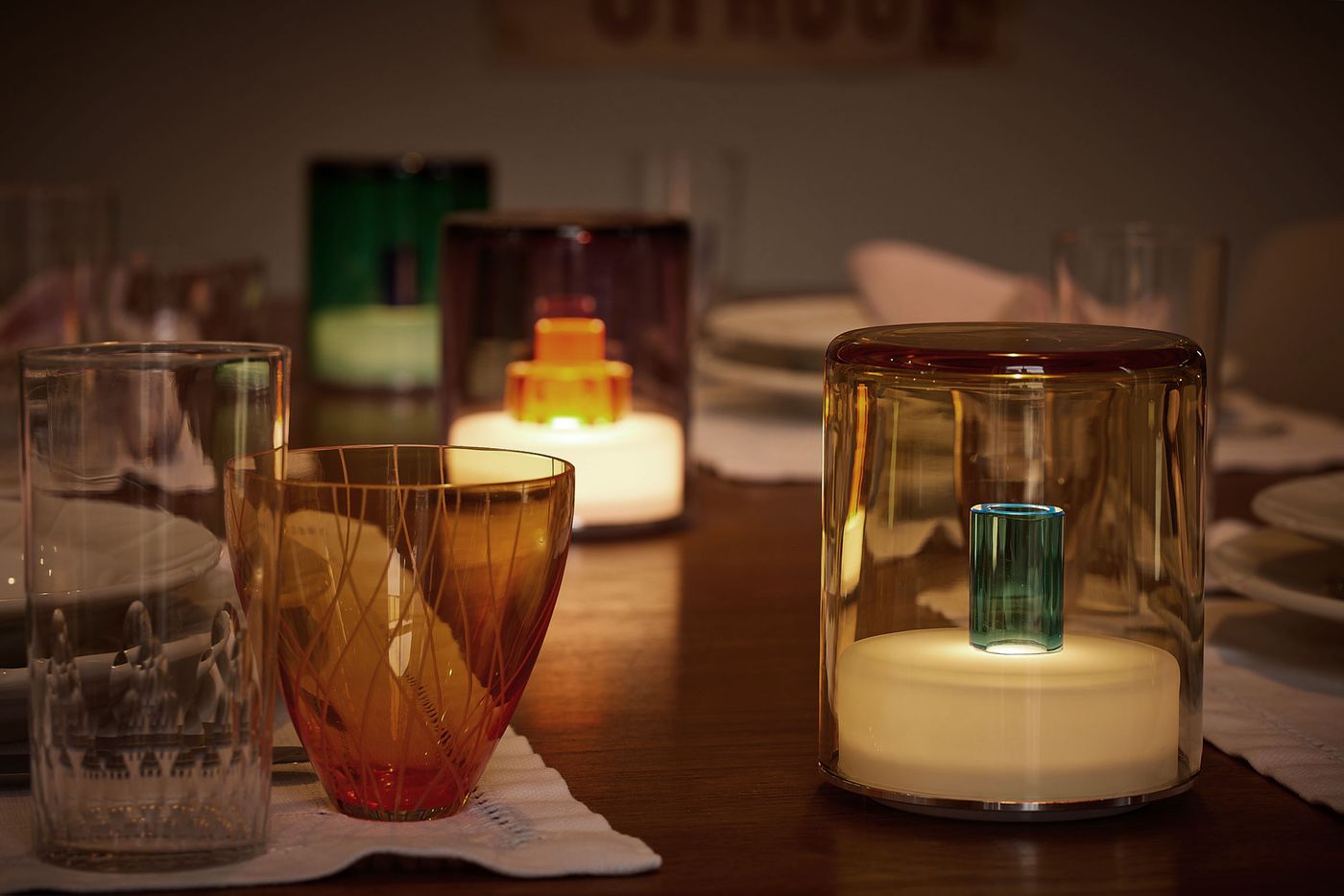 A symphony of jewel-toned glass lamps and colorful drinkware sets a moody, luxurious dinner scene.