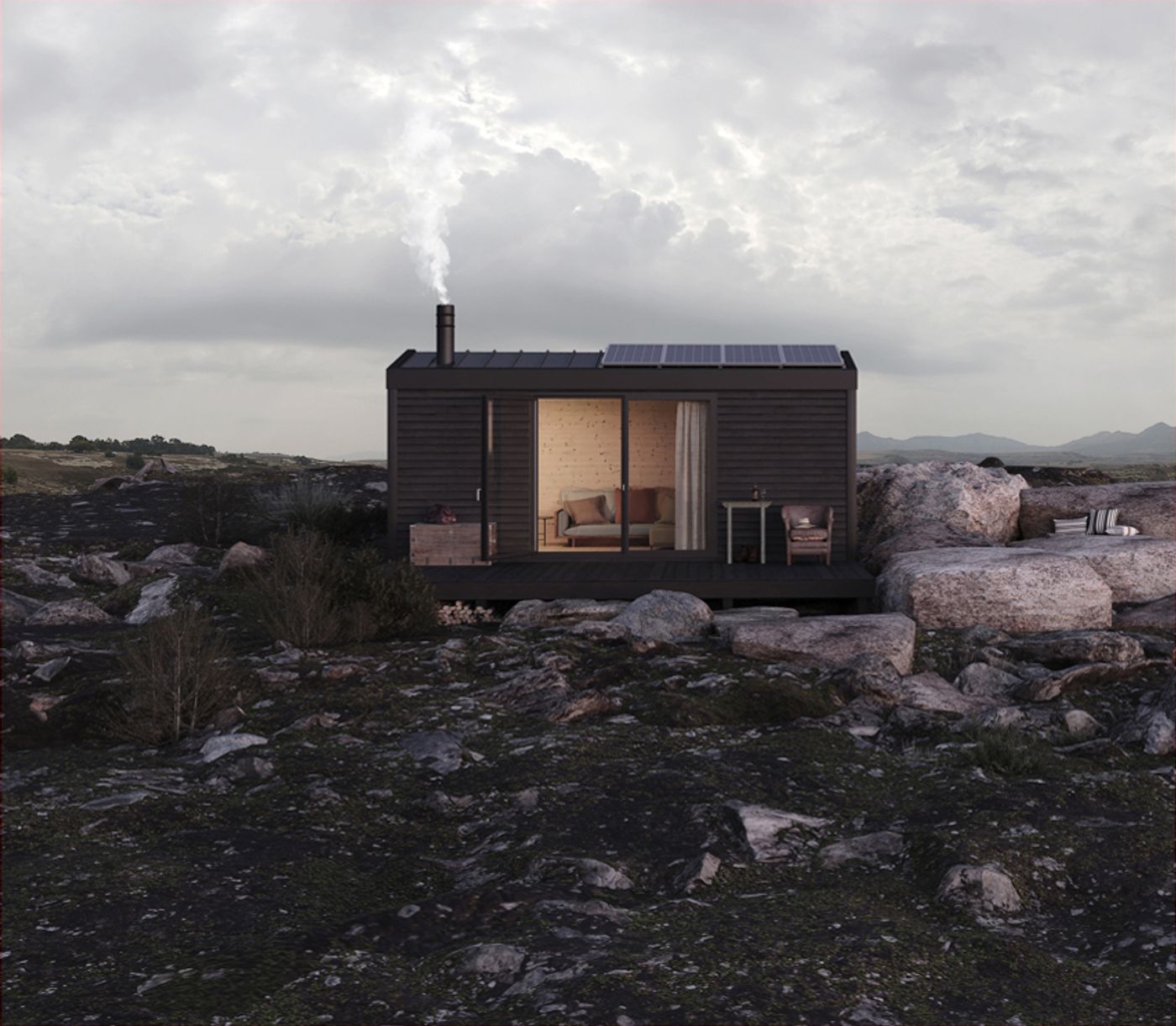 A minimalist, dark-clad modular cabin by Pedrez stands amidst a rugged, rocky landscape under an overcast sky. Smoke gently rises from its chimney, and an inviting warm light emanates from within, highlighting the interior through expansive sliding glass doors. This structure embodies a thoughtful integration of modern, sustainable design with a wild, untamed natural setting.