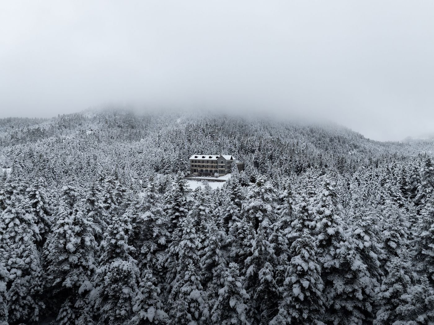 Panoramic shot of Manna Hotel emerging from a dense forest blanketed in snow. Panoramic shot of Manna Hotel emerging from a dense forest blanketed in snow.