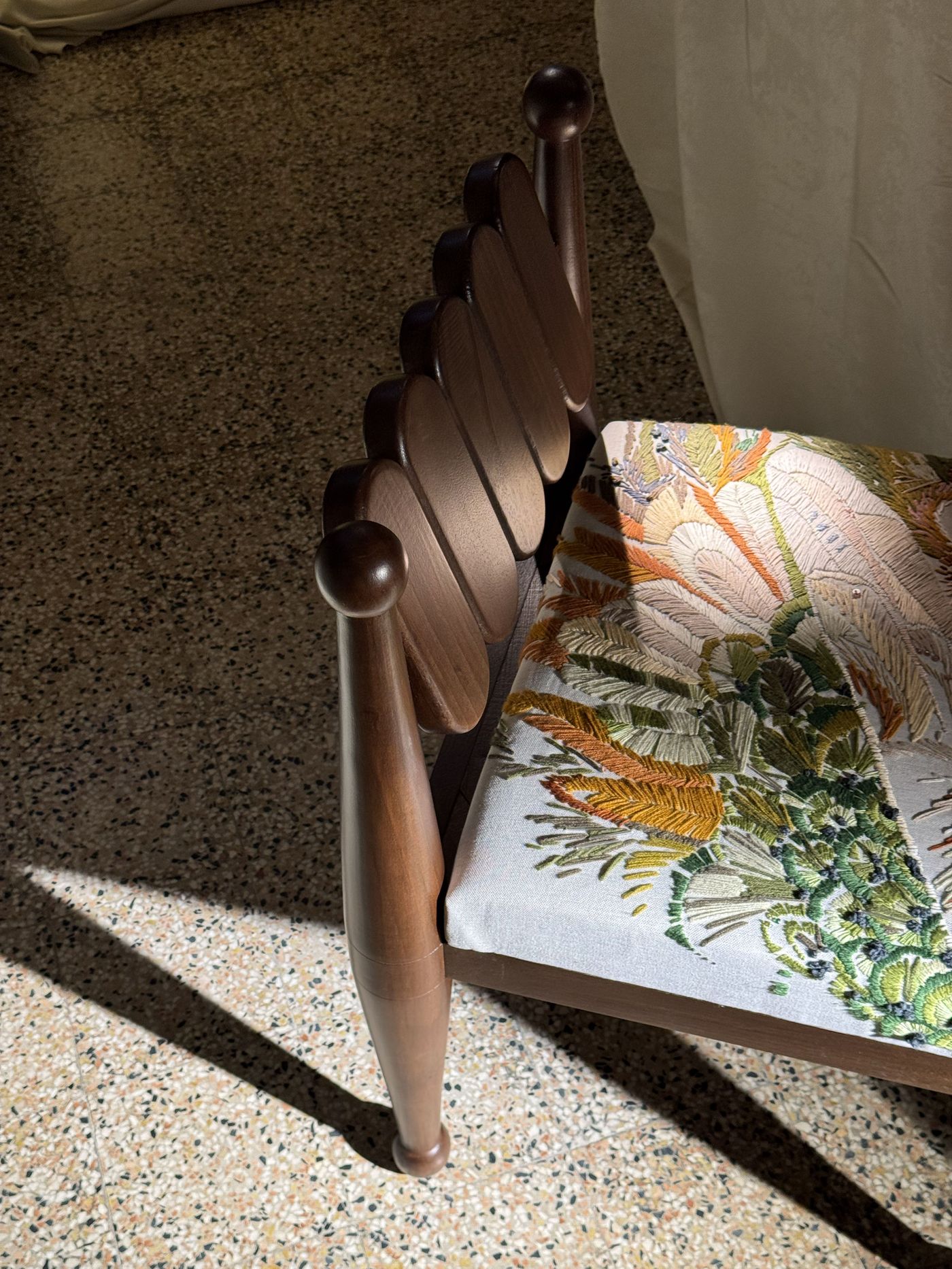 Close-up of a hand-carved wooden chair with playful rounded details and lush botanical embroidery, kissed by soft sunlight — craftsmanship in full bloom. Close-up of a hand-carved wooden chair with playful rounded details and lush botanical embroidery, kissed by soft sunlight — craftsmanship in full bloom.