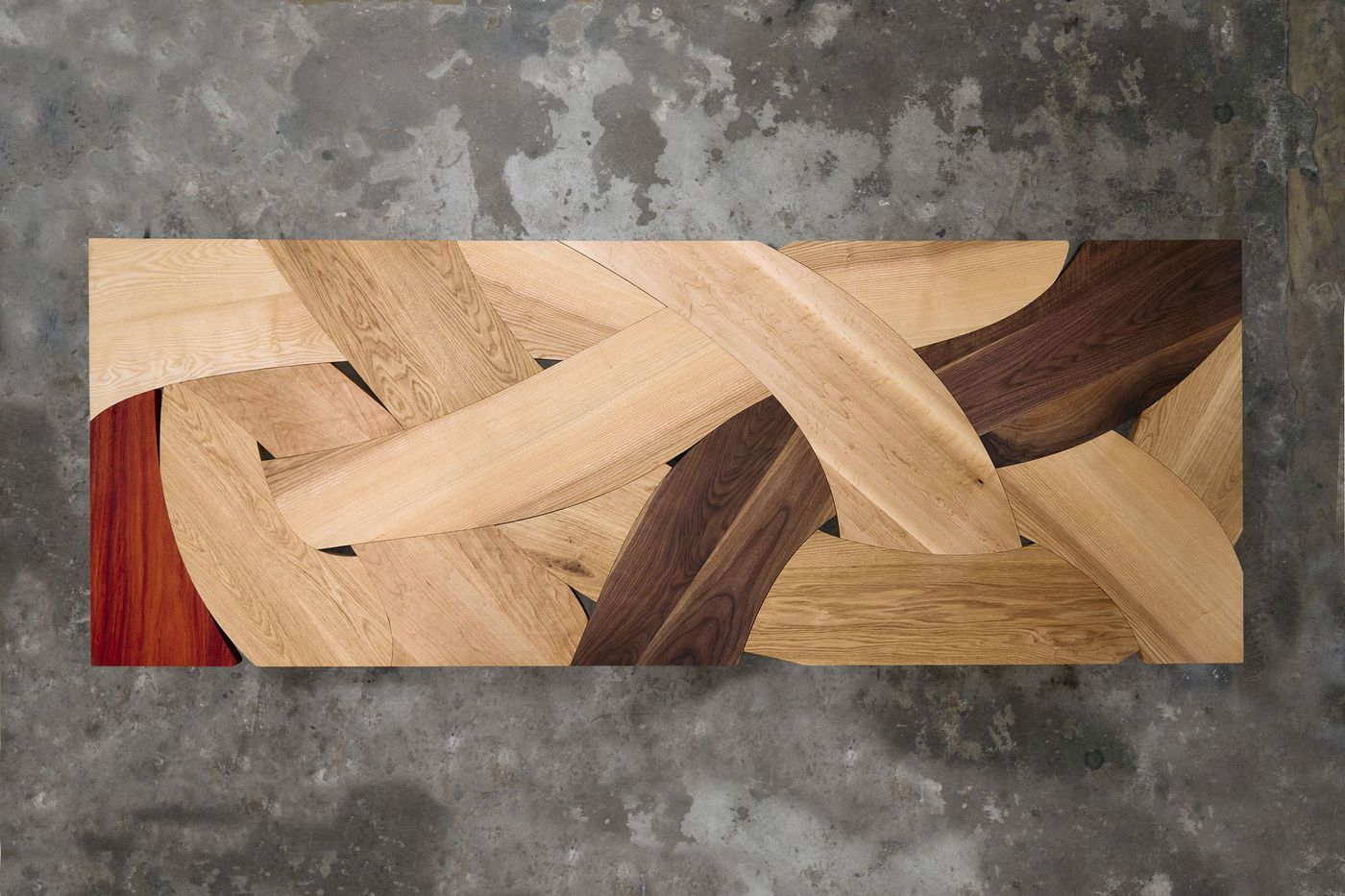 Overhead view of the same wooden table, showing the full abstract braid-like pattern of wood textures.
